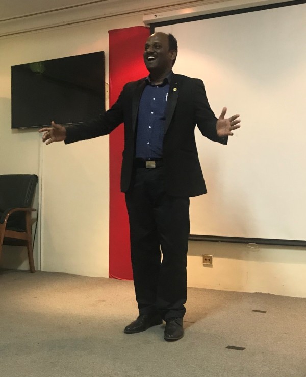 Riyadh Toastmaster Club 2017/2018 president standing on stage delivering a presentation to a crowd (audience not pictured). picture was taken in January 2018